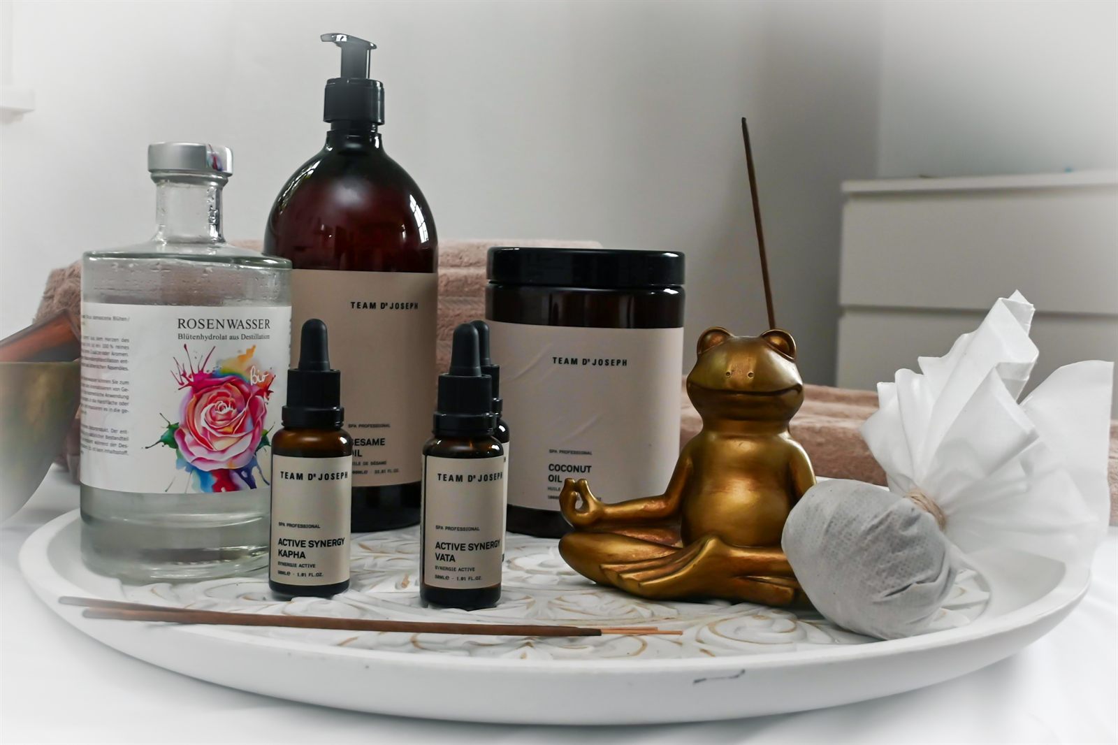 Ayurvedische Öle, Rosenwasser und Kräuterstempel auf einem Tablett
